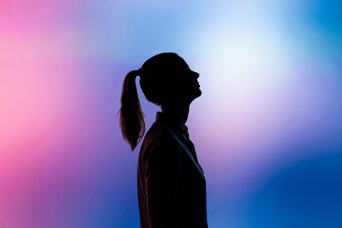 Silhouette of a woman with vibrant colors in the background.