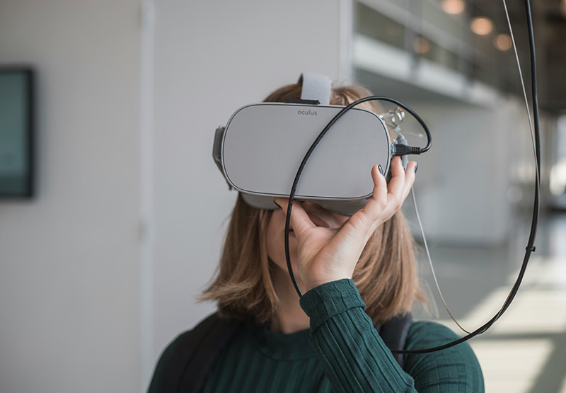 Stockimage of a woman useing a VR headset, covering her eyes.