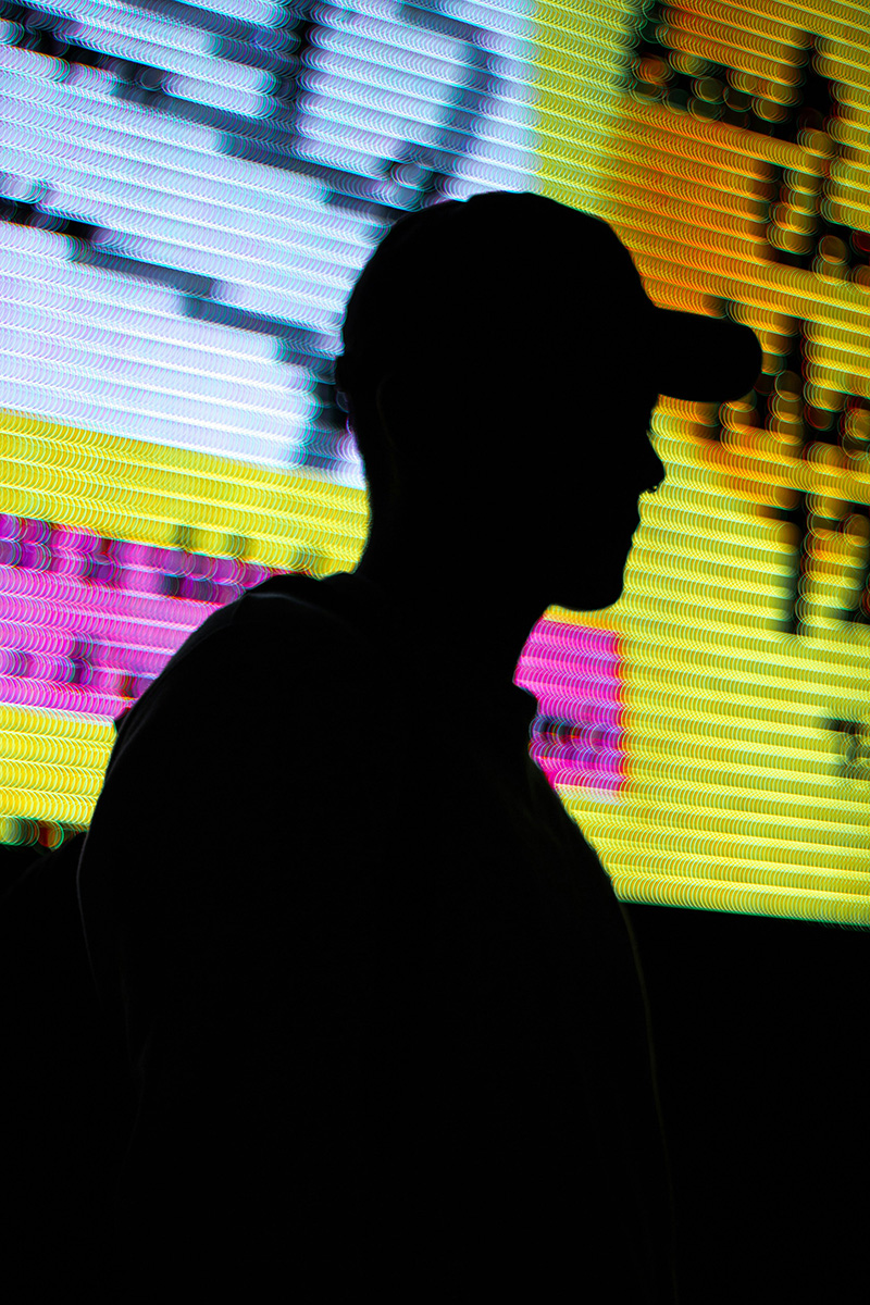 Stockimage of a man, photographed against the light in front of a colourful background.